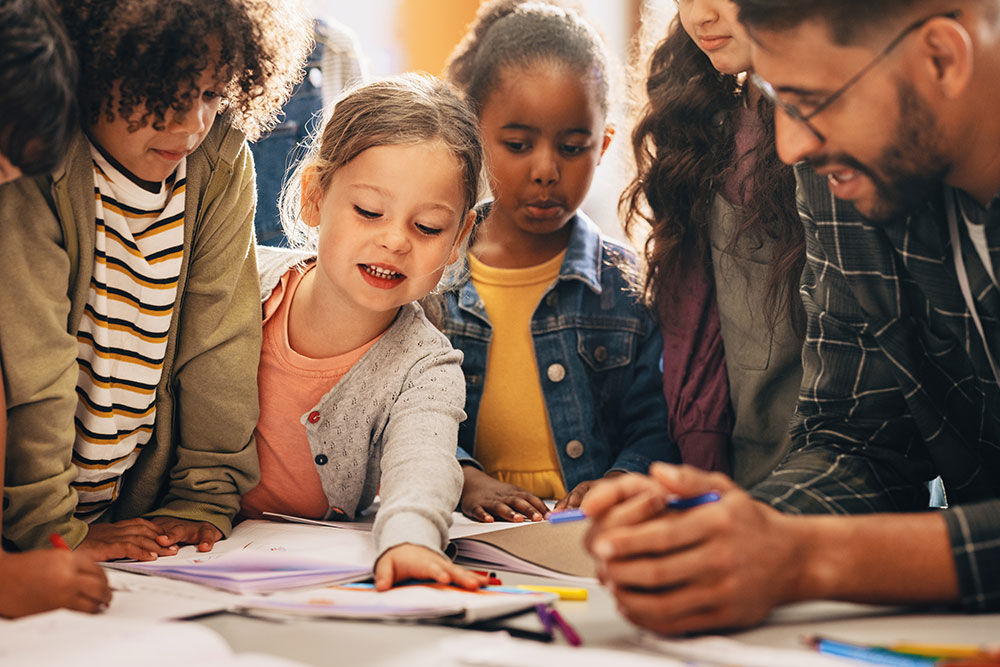 Image of teacher and students gathered around a table.